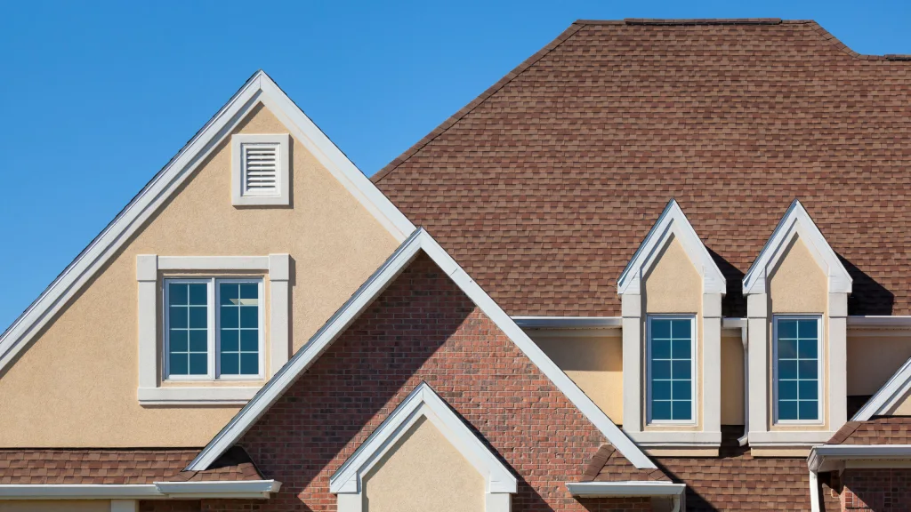 Residential home with tan stucco gable peaks, white trim, dormer windows and brick accents – Toms River Stucco